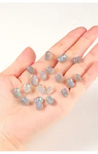 Detailed view of small carved grey moonstone beads with iridescent blue flashes held in hand