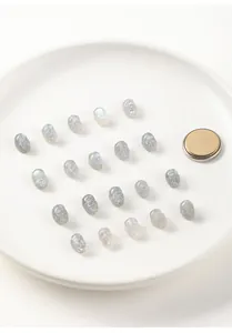 Detailed macro view of grey moonstone skull beads arranged on a white ceramic plate.