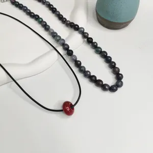 Vue détaillée d'un collier en perles de pierre naturelle et d'un pendentif rouge