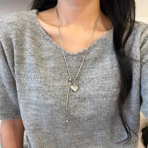 Detailansicht eines minimalistischen silbernen Herzanhängers an einer langen Kette