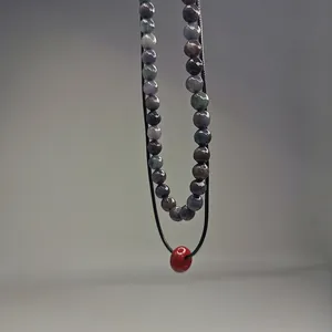 Vue détaillée de perles en pierre naturelle et pendentif donut rouge sur cordon noir