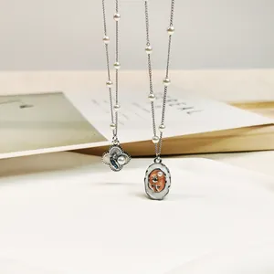 Macro detail of retro style necklaces featuring enamel painted flower and rose pendants