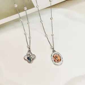 Macro view of vintage style oil-painted floral and oval pendants with pearl chain.