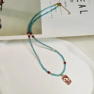 Detailansicht einer blauen Perlenkette im Retro-Stil mit goldenem Phönix-Anhänger.