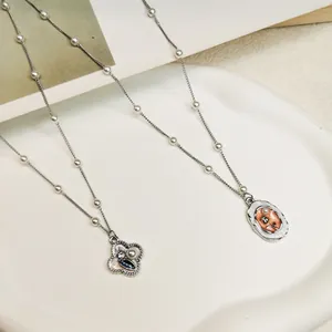 Detail of retro enamel pendants on pearl chains with vintage floral and abstract designs