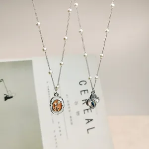 Detail view of two vintage-style necklaces with enamel pendants and pearl accents