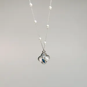 Detail of vintage silver necklace with clover pendant featuring pearl and blue crystal