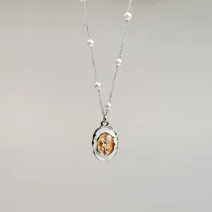 Detail of retro oil-painted flower necklace with pearl accents on a fine chain