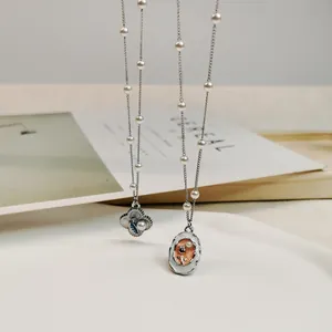 Close-up detail of vintage oil-dripped flower and oval pendants on a pearl chain necklace