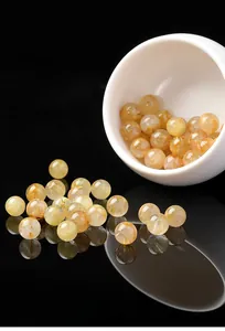 Dettaglio di perle di quarzo rutilato dorato che fuoriescono da una tazza bianca