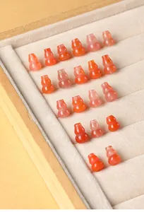 Macro detail of cherry red agate gourd-shaped beads arranged neatly in a jewelry display tray.