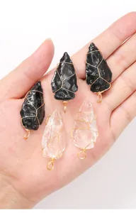 Detailed close-up of handmade wire-wrapped arrowhead crystal pendants in a hand