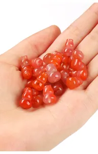Detailed view of small red agate gourd beads held in hand for DIY jewelry accessories