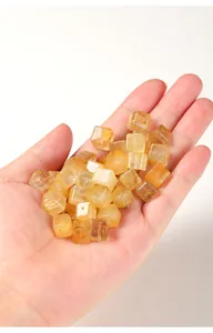 Macrodetail van natuurlijke gouden rutilated quartz kubuskralen in de hand