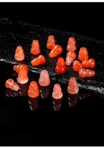 Detail view of small gourd-shaped cherry red agate beads on a black stone slab.