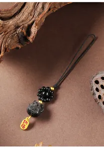 Detail eines schwarzen Glückskatzen-Anhängers mit goldenem Glücks-Tag