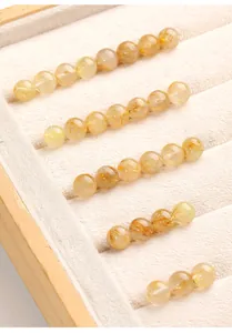 Dettaglio macro di perle tonde in quarzo rutilato dorato traslucido in un vassoio.