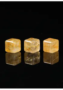 Gedetailleerde macro-weergave van drie gouden rutielkwarts kubuskralen met fijne naaldinsluitsels.