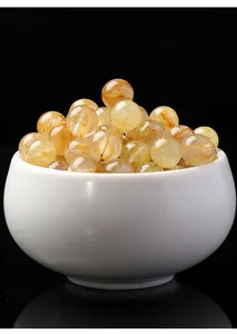 Primo piano di perle tonde in quarzo rutilato dorato di alta qualità in una ciotola bianca