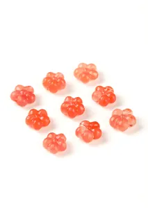 Macro view of nine translucent orange-red carved flower agate beads on a white background.