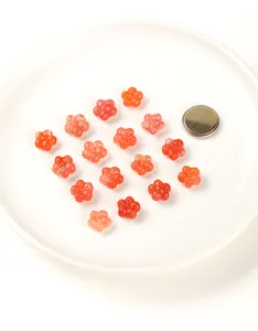 Macro view of carved red agate flower beads on a white plate with size reference