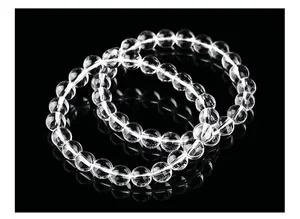 Vue détaillée de bracelets en perles de quartz blanc naturel sur un fond noir réfléchissant