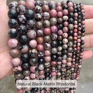 Vue détaillée de perles rondes en rhodonite naturelle à lignes noires de différentes tailles pour bijoux