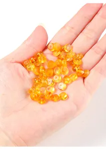 Lichtdurchlässige bernsteinfarbene Abakus-Abstandshalter-Perlen in der Hand für DIY-Schmuck