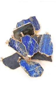 Détail macro de pendentifs irréguliers en lapis-lazuli et pierre de lune aux bords dorés.