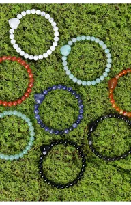 Detailopname van diverse natuurlijke kristallen kralenarmbanden met hartjes op een mosachtergrond