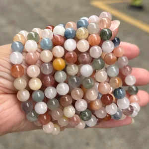 Macro view of several natural colorful rutilated quartz beaded bracelets held in hand.