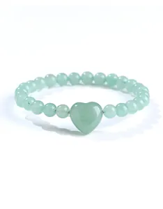 Gedetailleerde macro-opname van een groene natuurstenen kralenarmband met hartvorm.