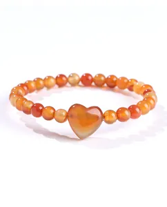Detail van een natuurlijke oranje carneool kralenarmband met gepolijste hartbedel