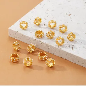 Primer plano de cuentas espaciadoras de flores doradas con perlas blancas.