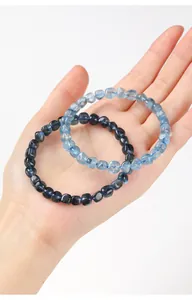 Close-up van twee natuurlijke blauwe en zwarte aquamarijn armbanden in een handpalm