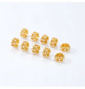 Primer plano de diez cuentas espaciadoras de flores doradas con perlas pequeñas