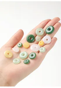 Gedetailleerd overzicht van gekleurde glazen donutkralen in jade-imitatie in de hand