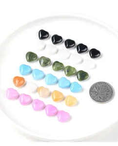 Colorful heart-shaped natural stone beads arranged on a white plate for size comparison.