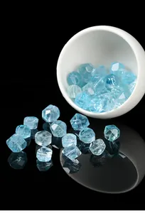 Close-up of light blue faceted natural topaz gemstones on black reflective surface