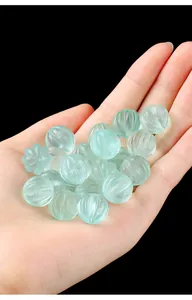 Hand-held macro shot of translucent green fluorite pumpkin beads with detailed ridges