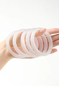 Detailopname van doorschijnende witte chalcedoon armbanden vastgehouden tegen wit