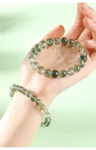 Gros plan d'un bracelet en quartz fantôme vert naturel porté à la main, vue détaillée