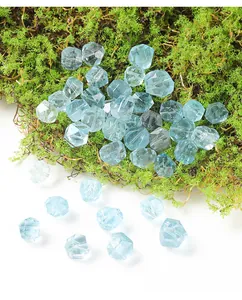 Close-up of icy clear sea blue natural topaz faceted irregular beads on green moss