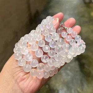 Détail d'un bracelet en pierre de lune bleue crème naturelle tenu à la main