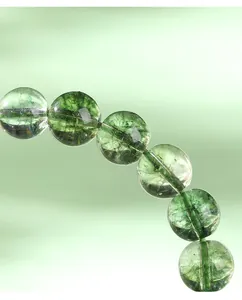 Gros plan de perles de cristal de quartz fantôme vert avec inclusions naturelles.