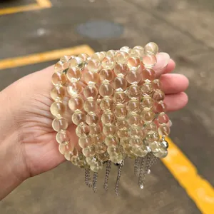Natürliches Zitronencitrin-Perlenarmband mit silbernen Kettenanhängern in der Hand