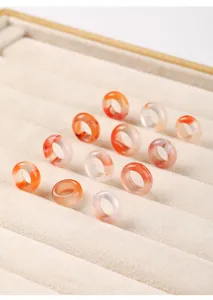 Macro view of natural ice-patterned Nan Hong agate rings on a beige velvet tray.