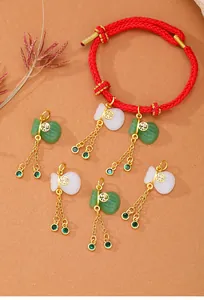 Vista detallada de dijes de bolsa de fortuna con circonitas verdes y pulsera roja