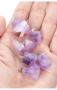 Close-up macro view of irregular raw purple amethyst crystal stone pendants on palm