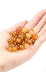 Gros plan de perles naturelles en quartz fantôme jaune dans une paume pour DIY.